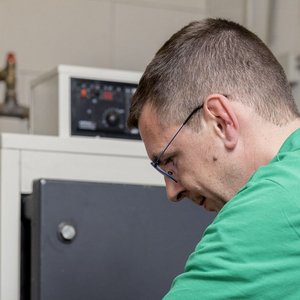 Der Techniker überprüft sorgfältig die Einstellungen eines Geräts, während er in einem industriellen Raum steht.