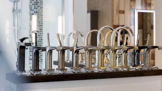 Verschiedene stilvolle Wasserhähne aus Metall stehen nebeneinander, jeder mit einzigartigem Finish und Form, in einem hellen Raum.