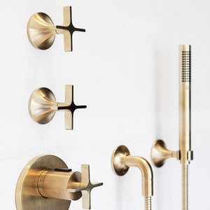 Eine elegante, goldene Armatur mit Kreuzgriffen an einer weißen Wand, die modern und stilvoll wirkt.