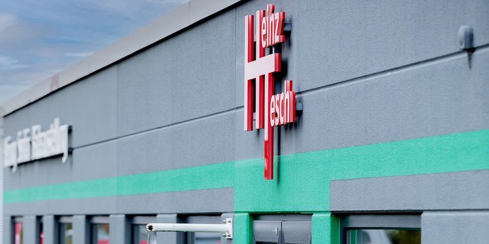 Die Fassade eines modernen Gebäudes mit einem auffälligen roten Schriftzug, der den Namen 'Heinz Tesch' zeigt.