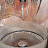 Moderne Armatur über stilvollem Waschbecken Ein elegantes, modernes Waschbecken mit einem gläsernen, facettierten Design, das vor einer kunstvollen Wandmalerei steht.