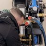 Der Handwerker überprüft sorgfältig die Rohre und Anschlüsse einer Heizungsanlage in einem modernen Raum.