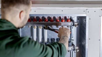 Der Techniker überprüft sorgfältig die Rohre und Ventile einer Heizungsinstallation in einem modernen Gebäude.