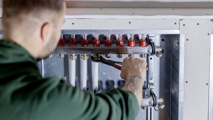 Präzise Arbeiten an einem Heizsystem mit Werkzeug Der Techniker überprüft sorgfältig die Rohre und Ventile einer Heizungsinstallation in einem modernen Gebäude.