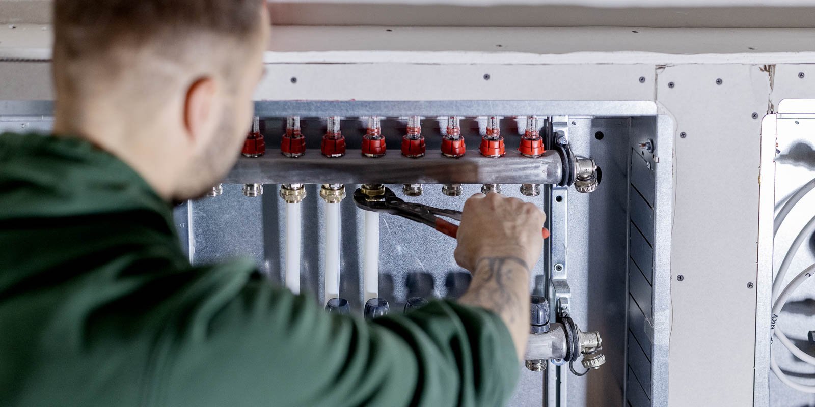 Der Techniker überprüft sorgfältig die Rohre und Ventile einer Heizungsinstallation in einem modernen Gebäude.