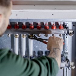 Der Techniker überprüft sorgfältig die Rohre und Ventile einer Heizungsinstallation in einem modernen Gebäude.