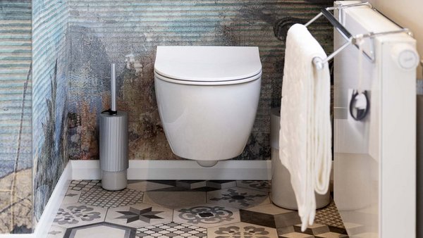 Ein modernes Badezimmer mit einer schwebenden Toilette, dekorativen Fliesen und einem eleganten Handtuchhalter an der Wand.