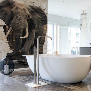 Elegantes Badezimmerdesign mit einer weißen Badewanne, einem runden Spiegel und einem großen Elefantenmotiv an der Wand.