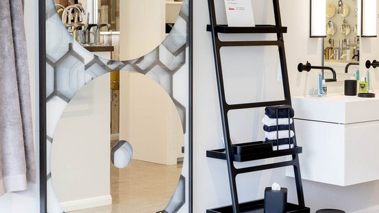 Ein modernes Badezimmer mit einem großen, runden Spiegel und einem eleganten Waschbecken, umgeben von stilvollen Accessoires.