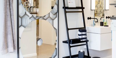 Ein modernes Badezimmer mit einem großen, runden Spiegel und einem eleganten Waschbecken, umgeben von stilvollen Accessoires.