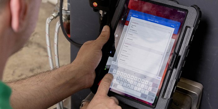 Auf dem Bildschirm des Tablets sind verschiedene Messwerte angezeigt, während eine Hand die Tastatur berührt.
