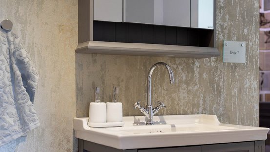 Ein elegantes Waschbecken mit einem modernen Wasserhahn und zwei Zahnbürstenhaltern auf einer weißen Ablage.